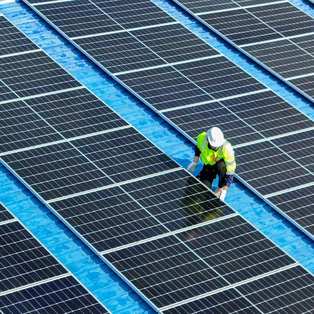 Worker working on solar panels system on roof